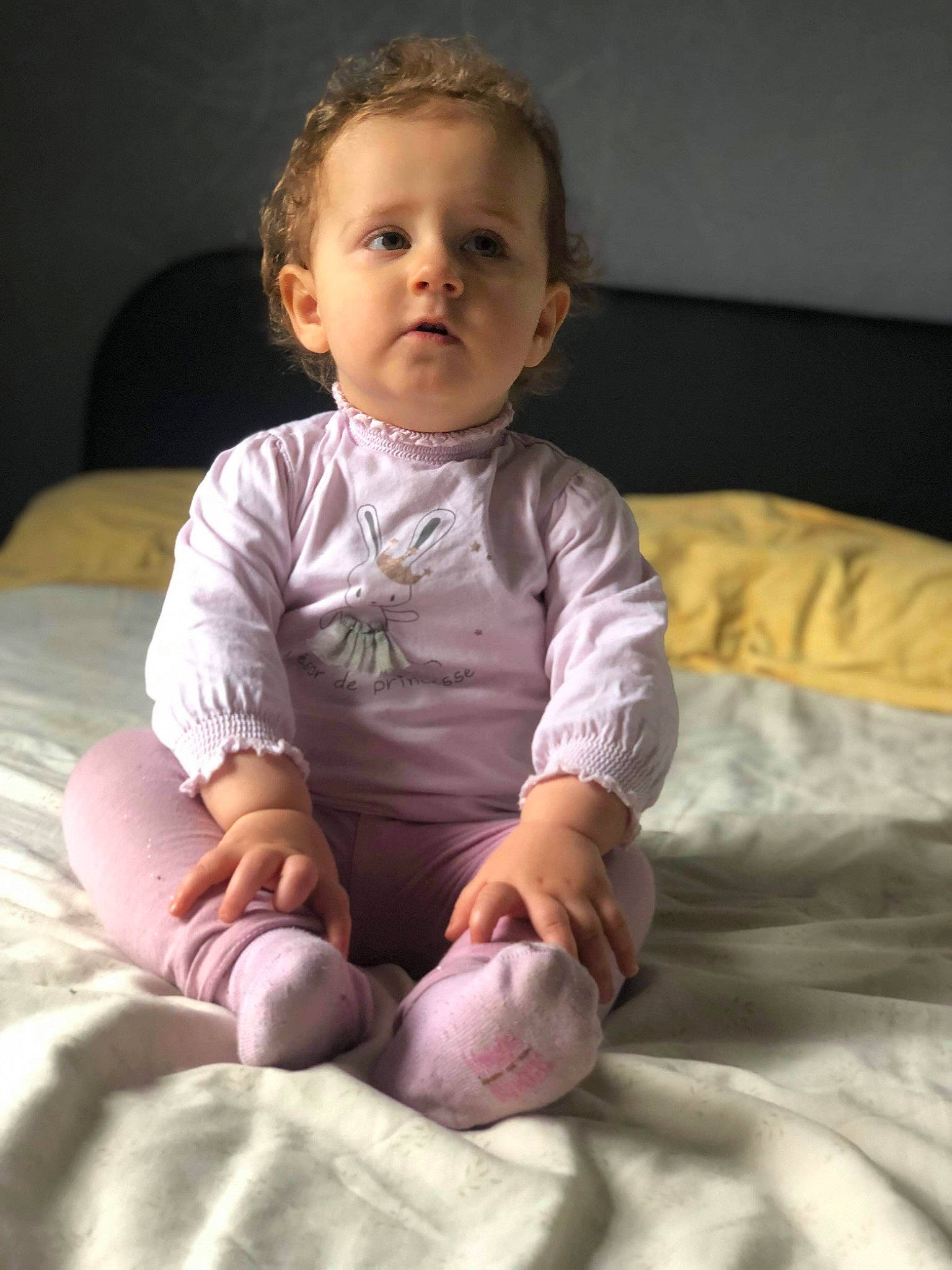 Ilyanna participe au concours pour gagner de l'argent avec cette photo : baby, baby_toddler_clothing, barefoot, cheek, child, chin, comfort, eye, facial_expression, flooring, foot, head, human_leg, knee, linens, person, room, sitting, skin, sleeve