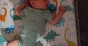 Estella is registered to the contest to win money with this photo: baby, bedtime, blanket, child, comfort, crib, cute, dinosaur_print, indoors, infant, mattress, newborn, onesie, pacifier, peaceful, rest, sleeping, soft_lighting, teddy_bear_print, toddler
