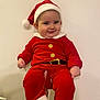 baby, child, santa_hat, red_clothing, holiday_outfit, smiling, cute, festive, indoor, person, portrait, hands, white_background, chubby_cheeks, christmas, holiday, infant, red_pants, red_sleeves, white_fur_trim