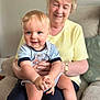 Alfie is registered to the contest to win money with this photo: baby, child, elderly_woman, smiling, indoor, living_room, person, sitting, happy, blue_eyes, clothing, hand_holding, shoe, couch, watch, short_sleeves, skin, hair, comfort, family