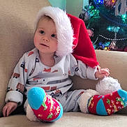 Ollie joined the competition — help win amazing prizes! toddler, child, santa_hat, christmas_tree, holiday, festive, socks, pajamas, couch, indoor, cute, smiling, decorations, lighting, soft, cozy, seasonal, happy, young_child, celebration