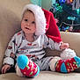 toddler, child, santa_hat, christmas_tree, holiday, festive, socks, pajamas, couch, indoor, cute, smiling, decorations, lighting, soft, cozy, seasonal, happy, young_child, celebration