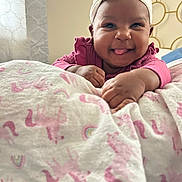 Journey joined the competition — help win amazing prizes! baby, headband, pink_clothing, blanket, unicorn_pattern, rainbow_pattern, indoor, happy, smiling, tongue_out, cute, child, infant, person, hand, face, soft_lighting, cozy, portrait, lying_down