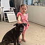 Tiana participe au concours pour gagner de l'argent avec cette photo : child, toddler, dog, pet, pink_dress, outdoor, concrete_floor, plant, bicycle, chair, stacked_chairs, wall, rustic, curly_hair, footwear, summer, calm, animal, person, gesture