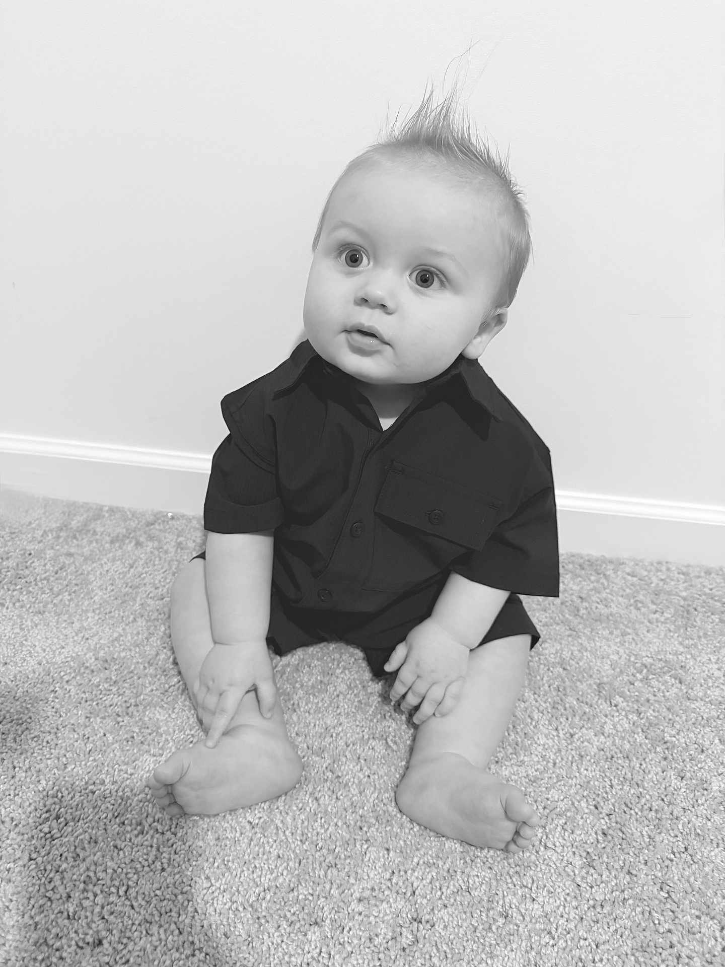 Carter is registered to the contest to win money with this photo: baby, infant, child, sitting, carpet, portrait, black_and_white, monochrome, shirt, short_sleeve, bare_feet, big_eyes, hair_spike, wall, baseboard, floor, indoor, cute, face, hands