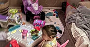 Katalayiah is registered to the contest to win money with this photo: blanket, carpet, child, colorful, cup, floor, hair, indoor, living_room, person, pink_chair, plastic_furniture, play_area, snack, sofa, table, toddler, toy_car, toys, window