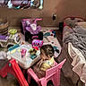 Katalayiah is registered to the contest to win money with this photo: toddler, child, pink_chair, table, toys, toy_car, snack, cup, living_room, carpet, blanket, sofa, window, play_area, floor, indoor, person, hair, plastic_furniture, colorful