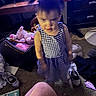 child, girl, dress, indoor, room, toys, stuffed_animal, shoes, carpet, book, furniture, cabinet, television, blur, motion_blur, messy, floor, pigtails, clothing, portrait
