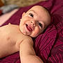 baby, smile, happy, face, arm, skin, blanket, lying_down, infant, cute, child, portrait, closeup, expression, young, human, indoors, warm_colors, soft_light, baby_skin