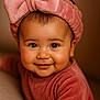 baby, child, smiling, headband, pink, bow, face, portrait, cute, infant, cozy, soft_texture, clothing, warm_lighting, close_up, happy, hand, indoors, skin, young