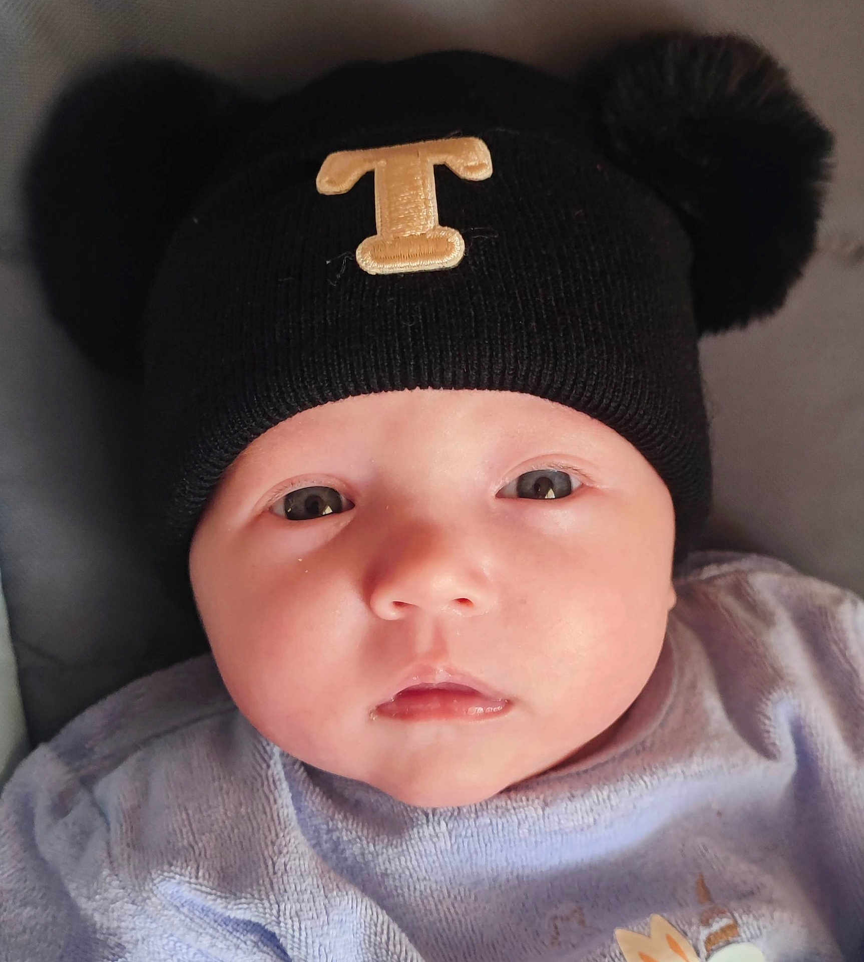 Taëlyna a rejoint le concours — aidez-le/la à gagner de superbes lots ! baby, infant, face, hat, black_hat, pom_poms, clothing, portrait, close_up, cute, child, skin, eyes, mouth, expression, headwear, soft_texture, indoors, young, person