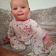 Madsen D is registered to the contest to win money with this photo: baby, child, pajamas, floral_pattern, couch, sofa, indoor, face, expression, motion_blur, foot, hand, person, cute, smiling, seated, cozy, soft_texture, home, playful