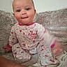 baby, child, pajamas, floral_pattern, couch, sofa, indoor, face, expression, motion_blur, foot, hand, person, cute, smiling, seated, cozy, soft_texture, home, playful