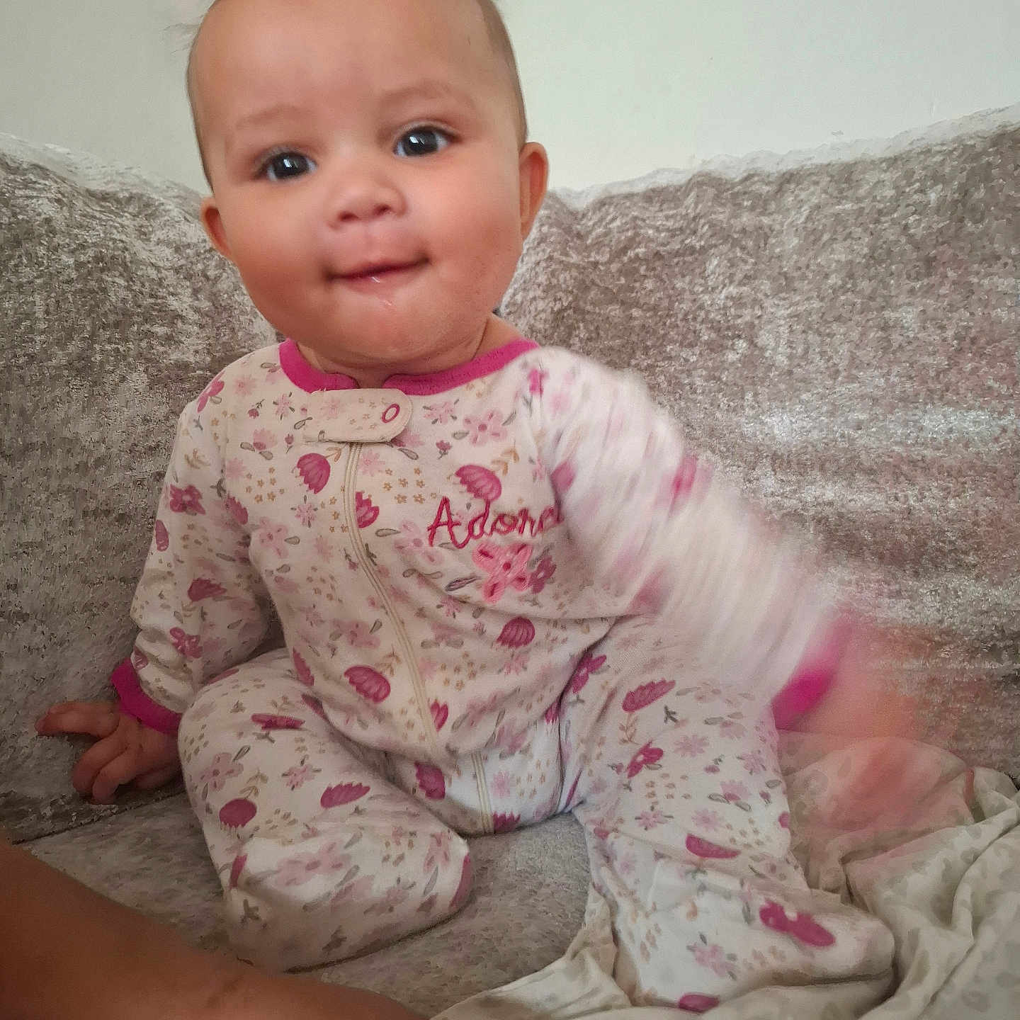 Madsen D is registered to the contest to win money with this photo: baby, child, pajamas, floral_pattern, couch, sofa, indoor, face, expression, motion_blur, foot, hand, person, cute, smiling, seated, cozy, soft_texture, home, playful