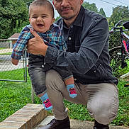 Esteban Muñoz joined the competition — help win amazing prizes! baby, child, man, outdoor, smiling, plaid_shirt, denim_jacket, grass, bike, fence, sidewalk, socks, elmo, casual_clothing, portrait, family, happy, tree, person, daylight