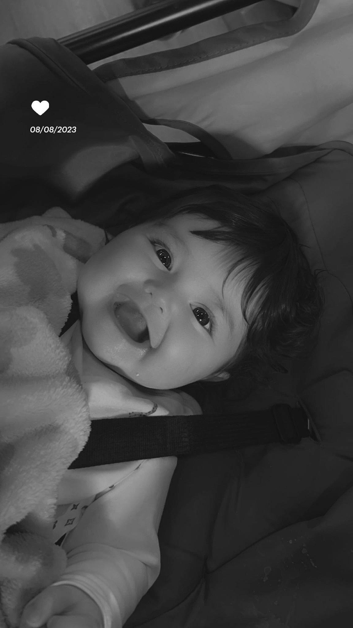 Thea is registered to the contest to win money with this photo: baby, baby_toddler_clothing, black_and_white, cheek, comfort, darkness, eyelash, flash_photography, gesture, happy, iris, lip, monochrome, monochrome_photography, mouth, nose, person, petal, smile, style