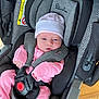baby, infant, car_seat, pink_clothing, hat, safety_harness, face, person, child, newborn, seat, fabric, indoor, cute, small, headwear, resting, comfort, protection, baby_gear