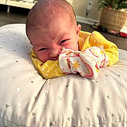 Dixie joined the competition — help win amazing prizes! baby, infant, pillow, yellow_clothing, face, expression, home_interior, floor, blanket, soft_texture, newborn, person, cute, lying_down, indoor, decor, pattern, closeup, head, sleeve