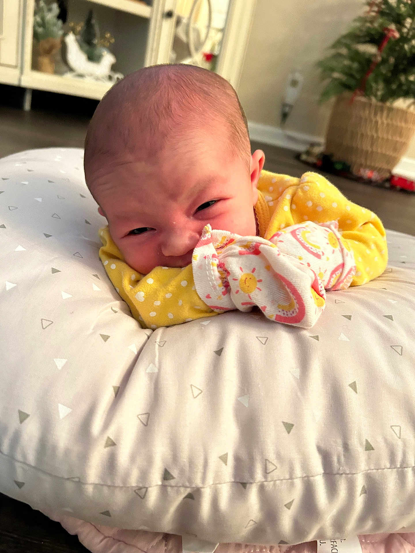 Dixie joined the competition — help win amazing prizes! baby, infant, pillow, yellow_clothing, face, expression, home_interior, floor, blanket, soft_texture, newborn, person, cute, lying_down, indoor, decor, pattern, closeup, head, sleeve