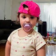 Cersei joined the competition — help win amazing prizes! toddler, child, pacifier, pink_cap, indoor, living_room, curtains, couch, wooden_floor, short_sleeve_shirt, person, young_child, face, hair, expressionless, standing, home, window, furniture, daylight