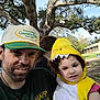 man, child, costume, dinosaur_costume, hat, outdoor, tree, park, smile, happy_gilmore, green_shirt, yellow, person, nature, daylight, casual, portrait, family, fun, cute