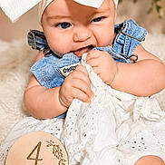 Rylee is registered to the contest to win money with this photo: baby, infant, child, headband, bow, denim, overalls, fabric, chewing, milestone, sign, wooden, blanket, cute, sitting, portrait, closeup, indoors, soft_texture, white