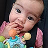 Rylee is registered to the contest to win money with this photo: baby, child, face, hand, toy, colorful, pink_shirt, car_seat, close_up, curious_eyes, fingers, long_eyelashes, infant, cute, portrait, indoors, seatbelt, playful, chewing, soft_background