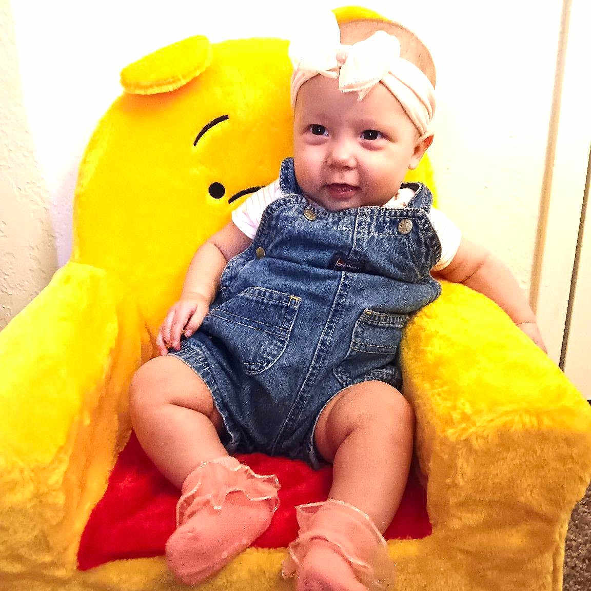 Hazel joined the competition — help win amazing prizes! baby, child, childhood, comfortable, cozy, cute, denim_overalls, furniture, happy, headband, indoor, infant, pink_socks, plush_chair, portrait, seated, smiling, soft_toys, yellow_chair, young_child
