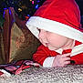 Colter is registered to the contest to win money with this photo: baby, carpet, child, christmas, cozy, crawling, cute, decorations, face, festive, gift_bags, holiday, holiday_lights, hood, indoors, infant, plaid_blanket, red_clothing, seasonal, smiling