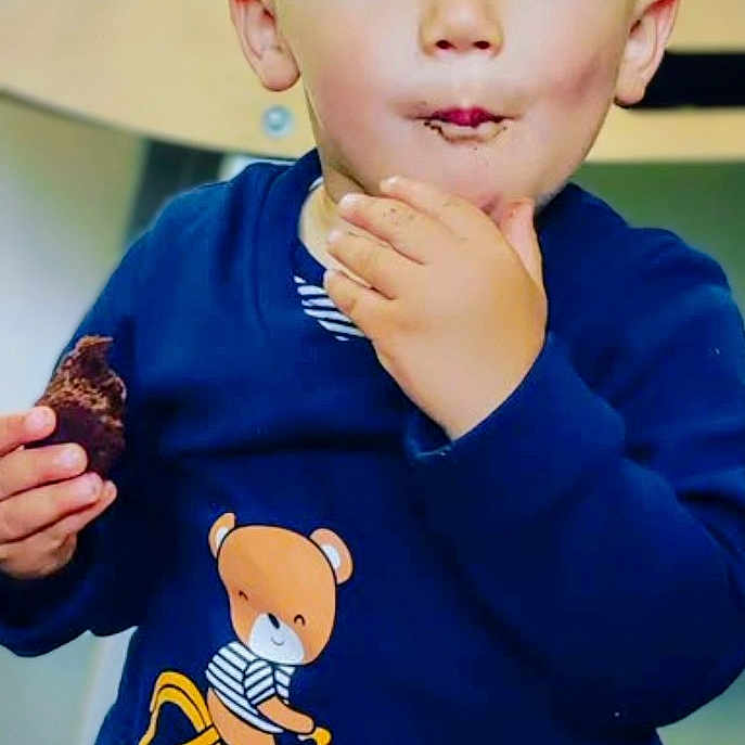 Hadj a rejoint le concours — aidez-le/la à gagner de superbes lots ! bear_graphic, bicycle, blue_eyes, casual_wear, chair, child, chocolate, clothing, cute, face, hand, happy, indoor, messy, portrait, smile, snack, sweater, toddler, young_child