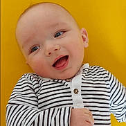 Hadj a rejoint le concours — aidez-le/la à gagner de superbes lots ! baby, baby_fashion, bright_background, cheerful, child, close_up, cute, eyes, face, hand, happy, human, infant, lying_down, portrait, skin, smiling, striped_clothing, yellow, young_child