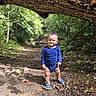 toddler, child, baby, standing, smiling, outdoors, forest, woodland, nature, trail, dirt_path, tree, branch, moss, leaves, blue_clothing, shoes, portrait, daylight, happy