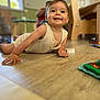 Loann participe au concours pour gagner de l'argent avec cette photo : baby, child, indoor, floor, toy, smiling, happy, person, furniture, wooden_floor, playing, infant, crawling, casual_clothing, daylight, room, blurred_background, cute, portrait, home