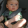 toddler, child, car_seat, seatbelt, green_shirt, curly_hair, indoors, baby, face, arms, legs, skin, expression, safety, straps, casual_clothing, light, shadow, portrait, candid