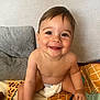 baby, smiling, diaper, child, indoor, cushion, blanket, patterned_blanket, happy, cute, sitting, skin, face, young_child, toddler, room, texture, colorful, infant, toy