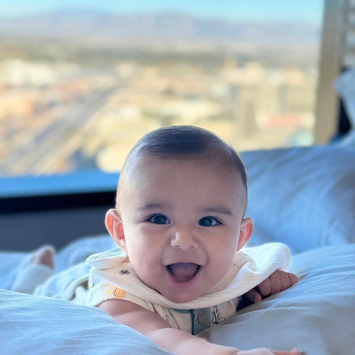 Nathan Benji is registered to the contest to win money with this photo: arm, baby, bed, bright, child, cityscape, clothing, cute, expression, face, happy, indoor, infant, person, pillow, portrait, skin, smiling, window, young