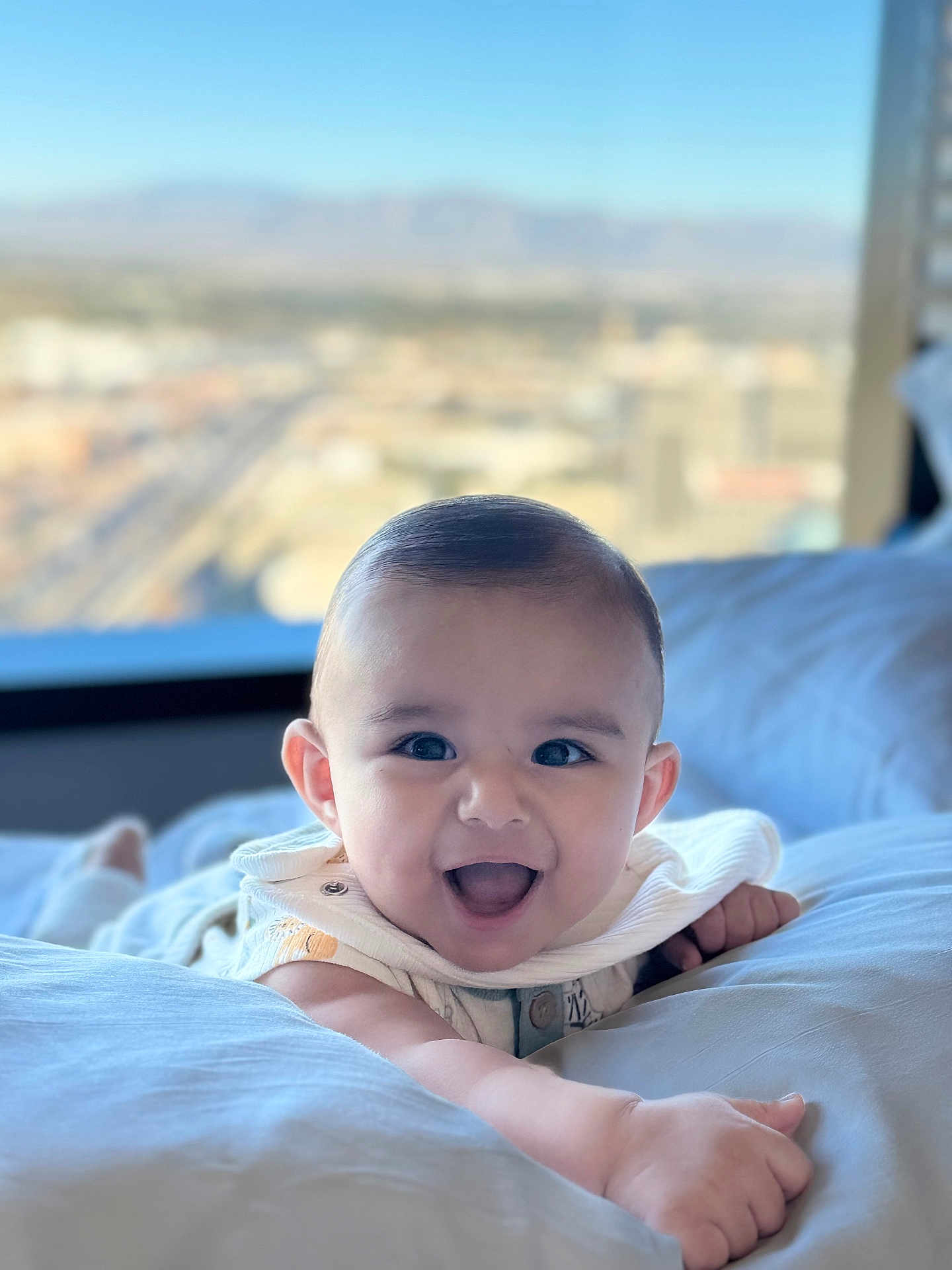 Nathan Benji is registered to the contest to win money with this photo: baby, smiling, infant, face, arm, bed, pillow, indoor, window, cityscape, happy, child, cute, person, skin, clothing, expression, portrait, young, bright