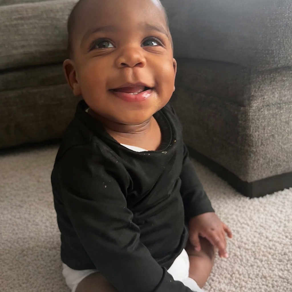 Kason is registered to the contest to win money with this photo: baby, child, smiling, sitting, carpet, indoor, black_clothing, white_diaper, happy, cute, portrait, infant, couch, living_room, toddler, person, young, small_child, face, hands