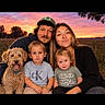 Waylan joined the competition — help win amazing prizes! children, family, adults, dog, pet, portrait, group_photo, outdoor, sunset, field, grass, smiling, sitting, siblings, parents, curly_hair, casual_clothing, t_shirt, nature, sky