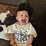 baby, infant, smiling, headband, bow, onesie, clothing, couch, pillow, cozy, happy, cute, child, person, indoors, skin, hand, sitting, mouth_open, expression