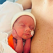 Gabin a rejoint le concours — aidez-le/la à gagner de superbes lots ! newborn, infant, baby, sleeping, nasogastric_tube, medical_tape, beanie, blanket, swaddled, tiny_hands, closeup, portrait, hospital, parent, chest, freckled_skin, peaceful, skin, healthcare, soft_lighting