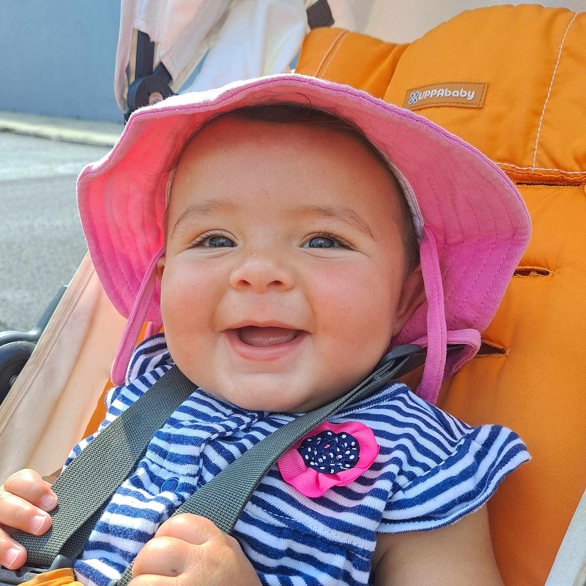 Sophia joined the competition — help win amazing prizes! baby, child, smiling, hat, pink_hat, striped_clothing, stroller, orange_stroller, happy, outdoor, sunlight, face, hands, cute, person, daylight, infant, joyful, closeup, summer