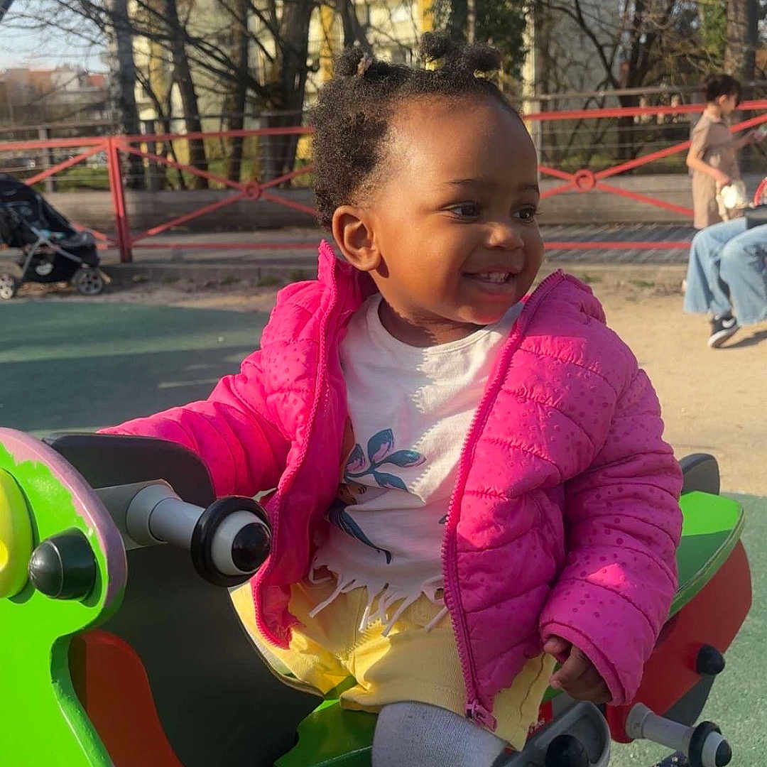Moidziwa participe au concours pour gagner de l'argent avec cette photo : toddler, child, playground, spring_ride, pink_jacket, smile, outdoor, daylight, play, fun, toy, sneakers, trees, park, fence, people, baby, happy, clothing, recreation