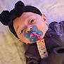 Ember is registered to the contest to win money with this photo: baby, pacifier, black_headband, bow, infant, face, clothing, lying_down, closeup, cute, child, person, soft_background, indoors, expression, head, portrait, sleepwear, accessory, young