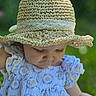 baby, child, hat, crocheted_hat, dress, blue_dress, floral_pattern, outdoor, nature, green_background, portrait, closeup, infant, cute, sun_hat, summer, soft_light, face, person, young_child