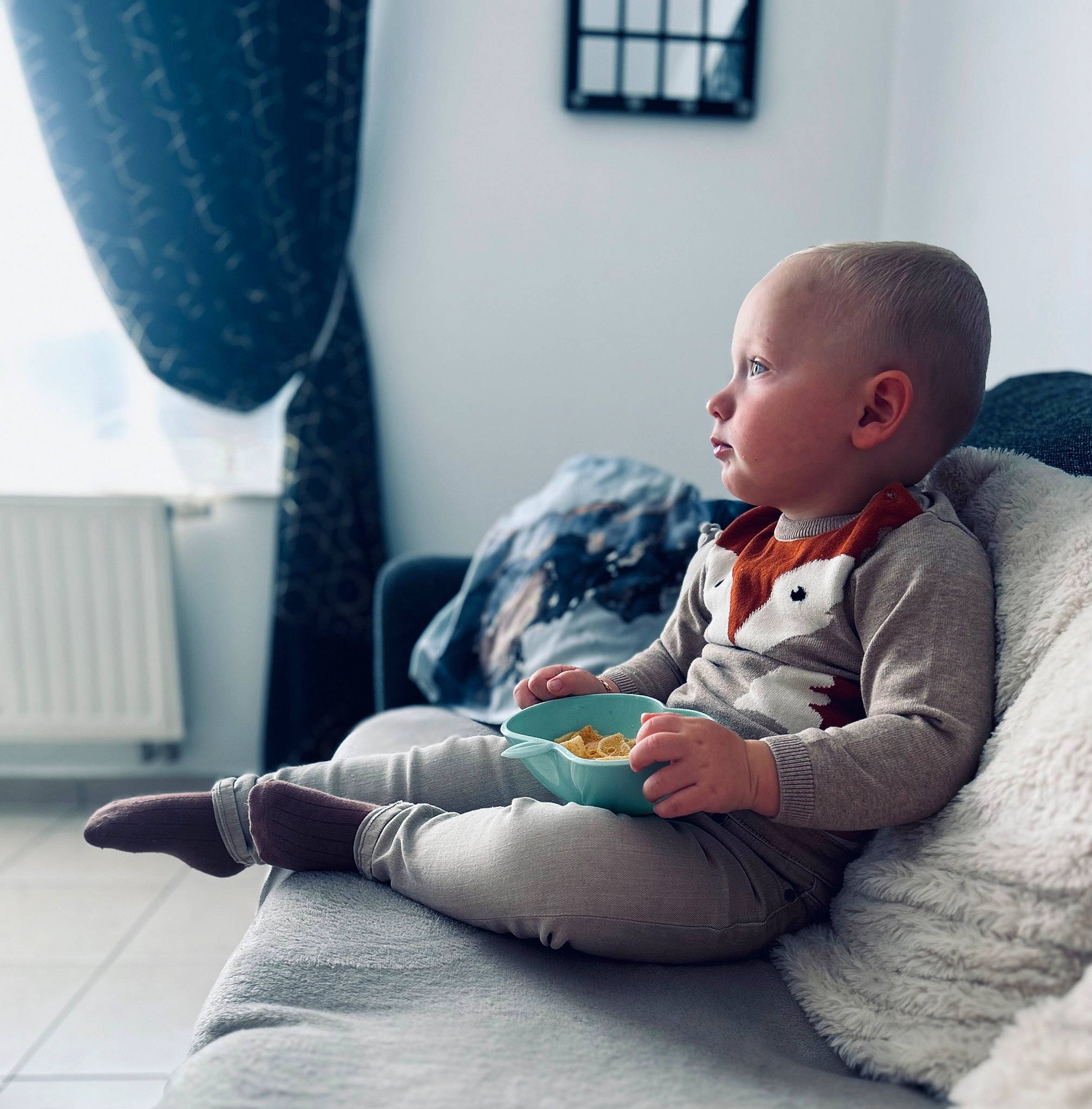 Matthia participe au concours pour gagner de l'argent avec cette photo : baby, baby_toddler_clothing, child, comfort, curtain, floor, flooring, foot, happy, human_leg, knee, lap, living_room, person, room, sitting, sock, standing, thigh, toddler