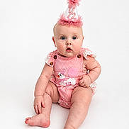 Hadley is registered to the contest to win money with this photo: baby, infant, child, portrait, birthday, party_hat, pink, outfit, sitting, wide_eyed, surprised, smiling, face, blue_eyes, studio, white_background, photography, celebration, lace, adorable