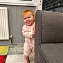 Amelie is registered to the contest to win money with this photo: toddler, child, red_hair, playful, indoor, couch, carpet, colorful, tongue_out, radiator, window, floor, barefoot, pajamas, smiling, cute, peekaboo, home, funny_face, person