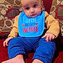 Priyansh Minhas joined the competition — help win amazing prizes! baby, child, bib, blue_clothing, barefoot, couch, cushion, indoor, patterned_fabric, person, portrait, sitting, soft_lighting, cute, infant, young_child, home, red_couch, comfortable, casual_clothing