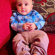 Priyansh Minhas joined the competition — help win amazing prizes! baby, child, infant, couch, plaid_shirt, patterned_cushion, red_couch, beige_pants, barefoot, indoor, portrait, sitting, cute, hands, feet, young_child, comfortable, curious, furniture, home